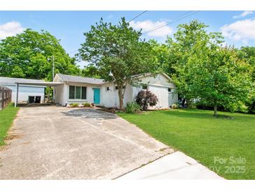 Charming home featuring a vibrant turquoise door, mature trees, and lush green lawn at 549 Spring Sw St, Concord, NC 28025