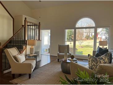 Inviting living room with large windows, a staircase, and neutral decor showcasing a bright and airy space at 9709 Calpher Ct, Matthews, NC 28105