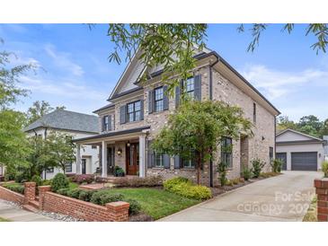 Brick two-story home with dark shutters, a front porch, and a landscaped yard at 1117 Churchill Commons Dr, Charlotte, NC 28211