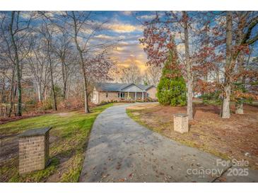 Charming single-story brick home with a long driveway and well-manicured lawn under a partially cloudy sky at 1115 Stony Point Rd, Kings Mountain, NC 28086