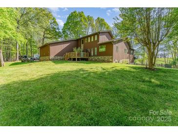 Expansive lawn and charming exterior with brown siding, stone accents, and a rear deck create an inviting outdoor space at 15215 Timberview Ln, Huntersville, NC 28078