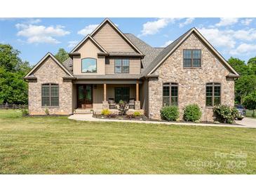 Charming stone-and-wood home featuring a covered front porch and well-manicured lawn at 174 Bellingshire Dr, Mt Ulla, NC 28125