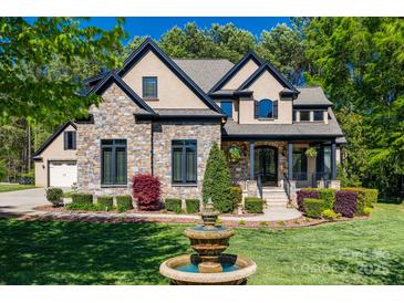 Beautiful stone and stucco home with a manicured front yard and a charming water fountain at 546 Little Cove Ln, Lake Wylie, SC 29710
