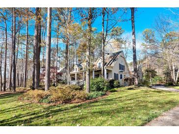 Two-story house with wrap-around porch, nestled among tall trees at 917 Patrick Johnston Ln, Davidson, NC 28036