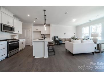 Open-concept living room with a modern kitchen, hardwood floors, and bright, natural light from the surrounding windows at 5680 Clear Creek Ln, Charlotte, NC 28215