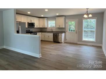 Bright kitchen features white cabinetry, stainless steel appliances, and a spacious layout with laminate floors at 718 Park Ave, Salisbury, NC 28144