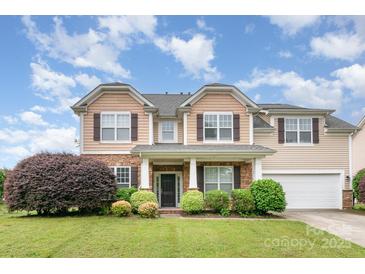 Charming two-story home with a stone facade, well-manicured lawn, and attached two-car garage at 11005 Magna Ln, Indian Trail, NC 28079