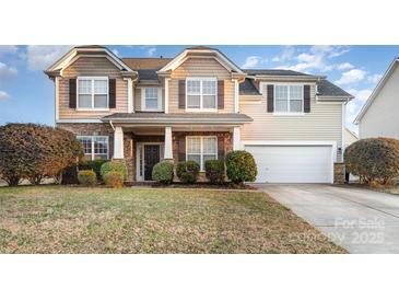 Charming two-story home with stone accents, covered porch, manicured landscaping, and a two-car garage at 11005 Magna Ln, Indian Trail, NC 28079