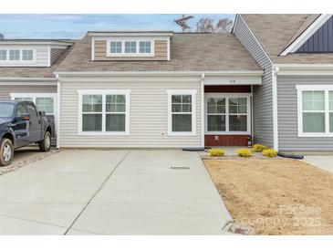 Tan and gray exterior of townhome with small front yard and driveway at 112 Canina Ln, Indian Trail, NC 28079