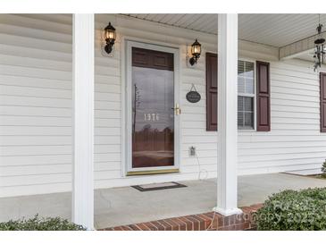 Inviting front entrance featuring a glass storm door, decorative lighting, and house number at 1976 Mcilwain Rd, Lancaster, SC 29720