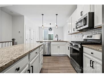 Modern kitchen featuring stainless steel appliances, white cabinets, granite countertops, and hardwood floors at 547 Old Mill Rd, Charlotte, NC 28206