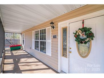 Covered front porch with white door, wreath, and ample light, offering a cozy and inviting entrance to the home at 150 Windmill Ct, Harmony, NC 28634