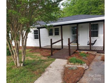 Charming exterior view of a white home with a covered porch, wooden walkway, and landscaped garden at 515 37Th Sw St, Hickory, NC 28602