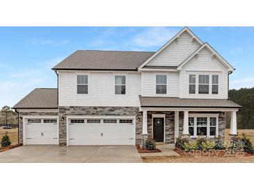 Charming two-story home with a stone and white shingle facade, two-car garage and covered front porch at 13019 Arnold Palmer Cir # 832, Lancaster, SC 29720