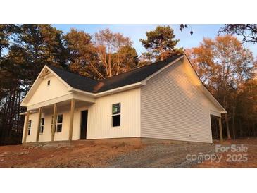 Newly constructed home with white siding, a covered porch and situated on a wooded lot at 1306 Eddie St, Gastonia, NC 28054