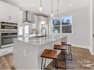 Beautiful open kitchen with white cabinets, quartz counters, stainless steel appliances, and wood-look floors at 8005 Elevate Ct, Charlotte, NC 28205