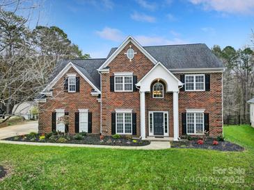 Brick two-story house with a landscaped lawn and a welcoming front porch at 7721 Sedgebrook E Dr, Stanley, NC 28164