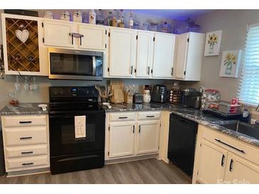 Well lit kitchen boasts white cabinets, stainless steel appliances, and modern countertops at 8905 Vagabond Rd, Charlotte, NC 28227