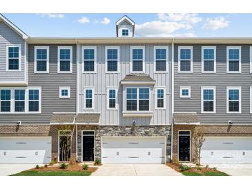 Three-unit townhome building with gray siding, white garage doors, and stone accents at 7108 Brookview Ln, Sherrills Ford, NC 28673