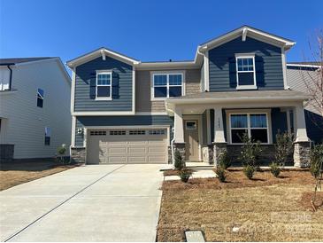 Charming two-story home with blue siding, stone accents, and a spacious two-car garage at 1447 Honey Trl, Monroe, NC 28112