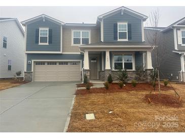 Two-story home features a two car garage, blue siding, stone accents and covered entryway at 1447 Honey Trl, Monroe, NC 28112