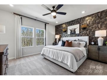 This bedroom features a ceiling fan, stylish wallpaper accent wall, and scenic outdoor views from the double windows at 1746 Blanche St, Charlotte, NC 28262