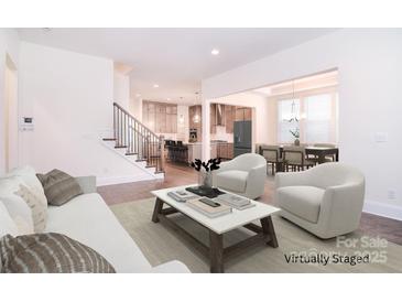 Spacious living room with hardwood floors, neutral tones, staircase, and seamless transition to kitchen and dining areas at 1364 Cedardale Ln, Denver, NC 28037