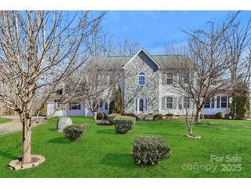 Charming two-story home with stone accents, well-maintained lawn, and mature trees at 1485 Adkin Dr, Iron Station, NC 28080