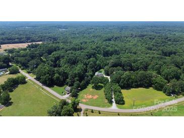Expansive aerial view of a wooded property with a home nestled among lush greenery and mature trees at 1769 Old Nc 27 Hwy, Mount Holly, NC 28120