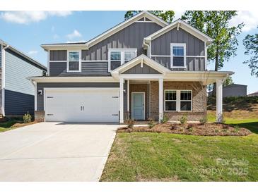 Charming two-story home featuring gray siding, brick accents, and a welcoming light blue front door at 115 Obadiah Ct, Troutman, NC 28115