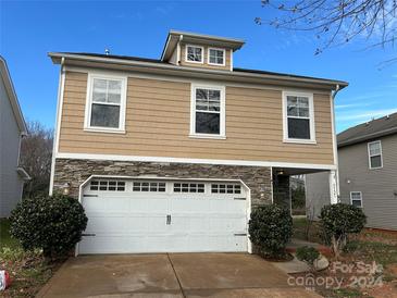 Tan two-story house with white two-car garage and landscaping at 5121 Stone Park Dr, Charlotte, NC 28269