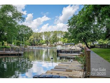 Picturesque waterfront view featuring a dock, boat, and serene lake reflecting the clear blue sky at 1934 Hickory Hills Dr, Denver, NC 28037