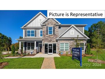 Two-story home with stone and gray siding, welcoming front porch, and landscaping at 1023 Canvasback Way, Indian Trail, NC 28079