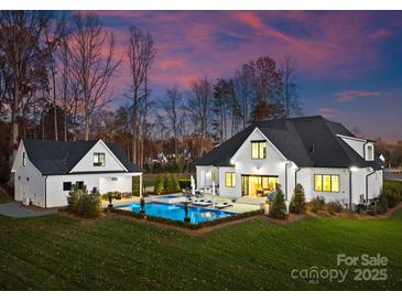 Stunning backyard with pool, detached garage, and lounge area at dusk at 124 Saylors Watch Ln, Mooresville, NC 28117