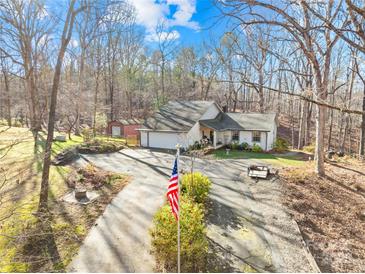 Single story home with a large driveway and American flag, nestled in a wooded area at 911 Wildwood Dr, Kings Mountain, NC 28086