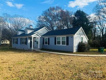 Charming single-story home featuring a light blue exterior with dark shutters and mature trees around the property at 2801 Cowles Rd, Charlotte, NC 28208