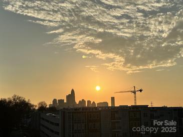 Sunrise view of the city skyline, with modern condos and a construction crane silhouetted against the bright sun at 2338 Yadkin Ave # 505, Charlotte, NC 28205