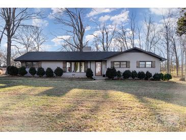 Brick ranch house with dark trim, landscaping, and a large yard at 605 Impala Dr, Albemarle, NC 28001