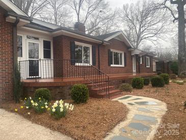Charming brick home featuring manicured landscaping, a cozy front porch, and decorative flowerbeds at 936 N 5Th St, Albemarle, NC 28001
