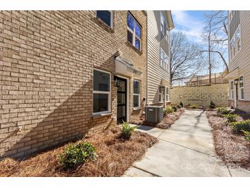 Brick and vinyl exterior detail with small garden, paved walkway, and shade tree at 3709 Lou Ann Ave, Charlotte, NC 28208