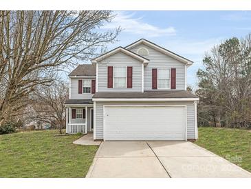 Two-story home featuring a gray exterior, white garage door, well-manicured lawn, and mature trees at 8702 Wood Sorrel Ct, Matthews, NC 28105