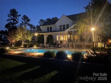 Stunning backyard oasis featuring a sparkling pool, expansive deck, and landscape lighting at 116 Cedar Branch Ct, Mooresville, NC 28117