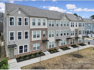 A view of gray townhouses featuring brick accents, symmetrical windows, and landscaped front yards on a sunny day at 2013 Federation Ct, Charlotte, NC 28205