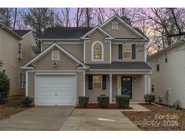 Two-story house with beige siding, white garage door, and landscaping at 2604 Cochrane Dr, Charlotte, NC 28269