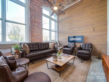 Spacious living room featuring leather furniture, a wood coffee table, and large windows at 201 S Hoskins Rd # 122, Charlotte, NC 28208