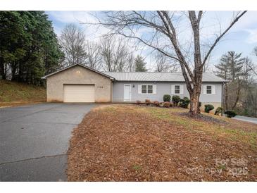 Ranch style home with gray siding, attached garage, and a tree in the front yard at 7704 Woodland Hills Rd, Hickory, NC 28602