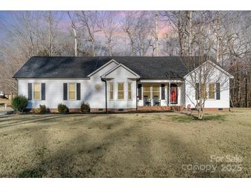 White house with red door, two rocking chairs on porch, and well-manicured lawn at 101 Ingonish Dr, Gastonia, NC 28056