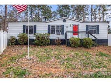 Charming single-story home with white siding, black shutters, a vibrant red door, and an American flag at 114 Catawba Woods Ct, Belmont, NC 28012