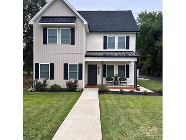 Two-story house with gray and white siding, black shutters, and a covered porch at 114 E 5Th Ave, Gastonia, NC 28052