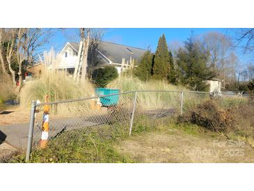 View of a house behind a chain link fence and overgrown grass at 123 E Branch Ave, Shelby, NC 28152